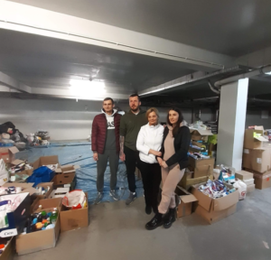 Zdjęcie przedstawia panią dyrektor WPSP oraz wolontariuszy pomagających sortować dary dla uchodźców w postaci pampersów, żywności i tym podobnych.