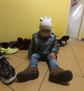 zdjęcie przedstawia malutkie dziecko z Ukrainy siedzącego na podłodze.