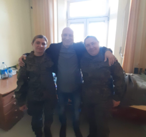 Zdjęcie przedstawia pracownika naszego szpitala oraz dwóch wojskowych pomagających przy uchodźcach z Ukrainy.