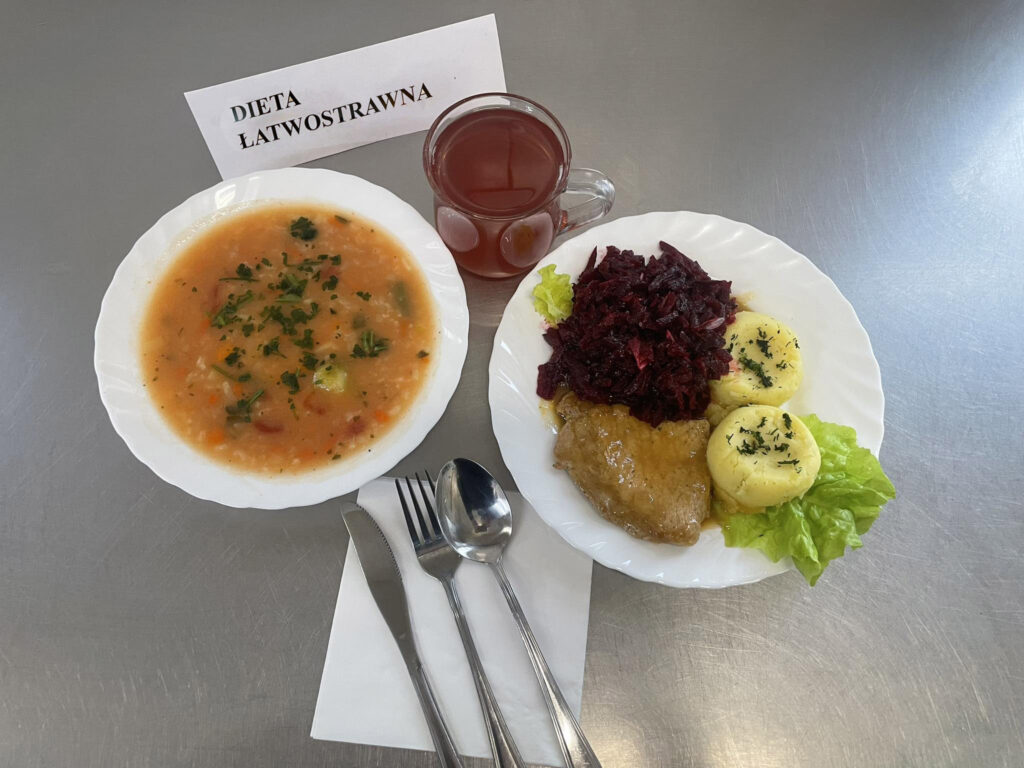 zdjęcie obiadu złożonego z: zupy pomidorowej, bitki, ziemniaków, sałatki z buraków oraz kompotu.