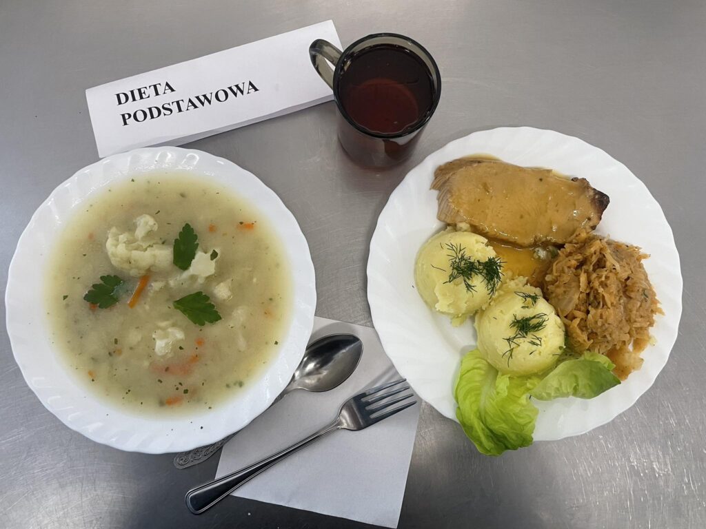 zdjęcie obiadu złożonego z: zupy kalafiorowej z makaronem, schabu, ziemniaków, kapusty zasmażanej oraz kompotu.
