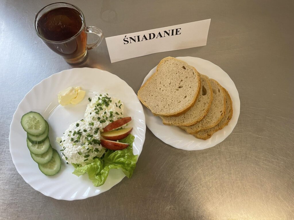 zdjęcie śniadania złożonego z: twarogu ze szczypiorkiem, chleba, margaryny oraz herbaty.