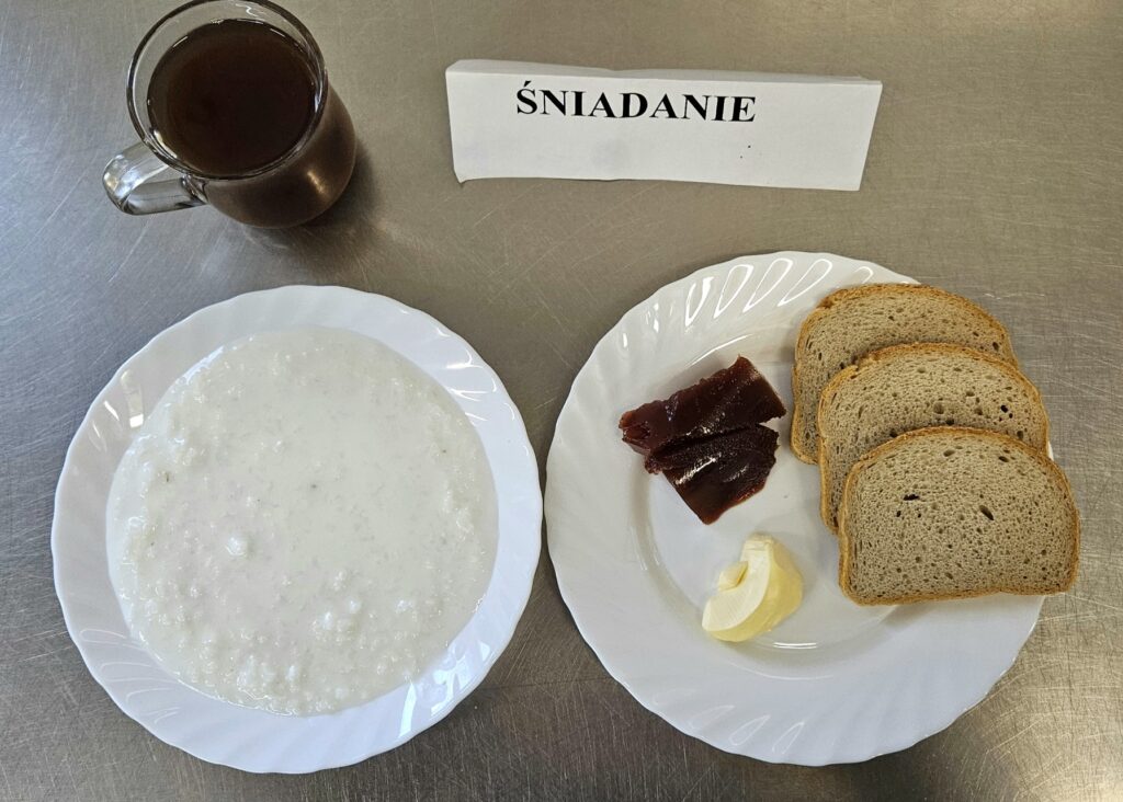 zdjęcie śniadania złożonego z: zupy mlecznej, chleba, margaryny, dżemu oraz herbaty.