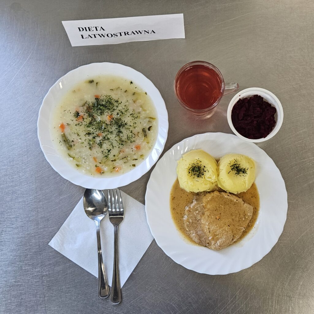 zdjęcie obiadu złożonego z: zupy ogórkowej z ryżem, bitki, ziemniaków, sałatki z buraków oraz kompotu.
