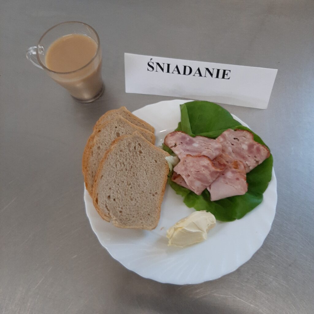 zdjęcie śniadania złożonego z: szynki konserwowej, sałaty zielonej, chleba, margaryny oraz kawy z mlekiem.