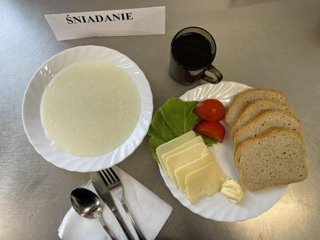 zdjęcie śniadania złożonego z: grysiku na mleku, bułki, sera twardego, margaryny oraz herbaty.