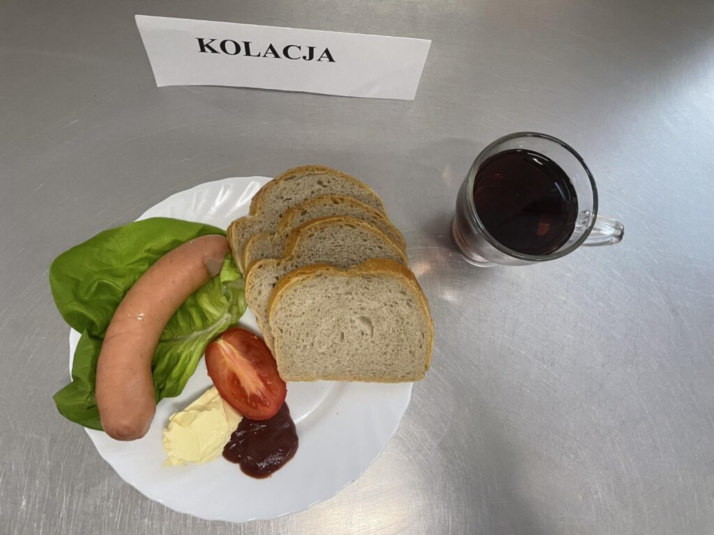 zdjęcie kolacji złożonej z: parówki, ketchapu, chleba, margaryny oraz herbaty.
