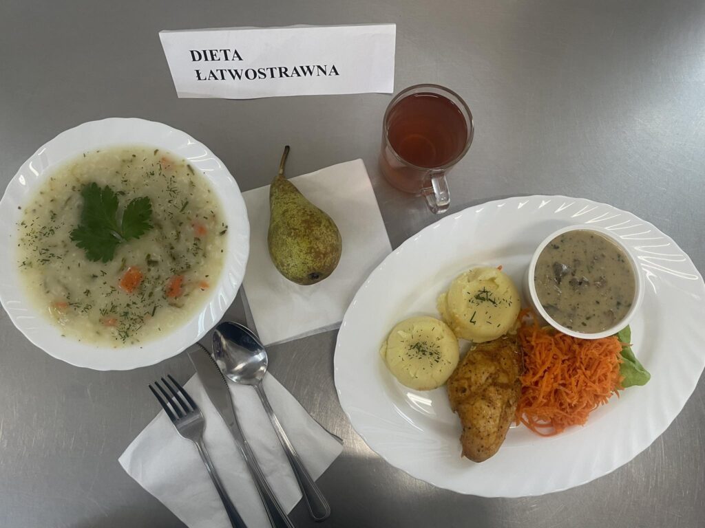zdjęcie obiadu złożonego z; zupy ogórkowej z ryżem, piersi kurczaka w sosie pieczarkowym, ziemniaków, marchwi z chrzanem, kompotu oraz gruszki.