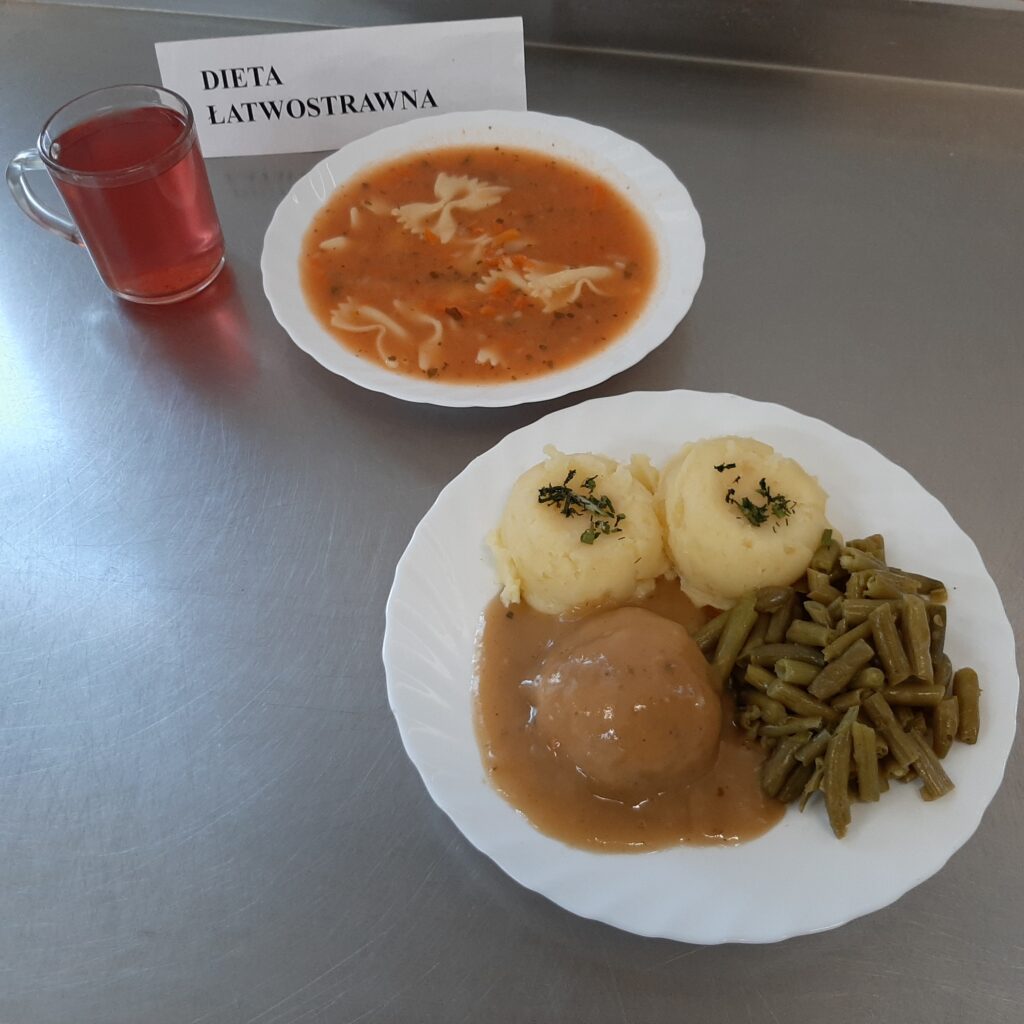zdjęcie obiadu złożonego z: zupy pomidorowej z makaronem, pulpeta w sosie, ziemniaków, fasoli szparagowej oraz kompotu.