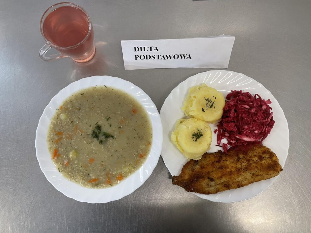 zdjęcie obiadu złożonego z: zupy krupnik, ryby panierowanej, ziemniaków, surówki z kapusty i buraka oraz kompotu.