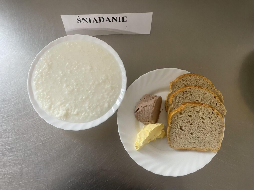 Zdjęcie śniadanie złożonego z:ryżu na mleku, pasztetu mazowieckiego, chleba, margaryny oraz herbaty.