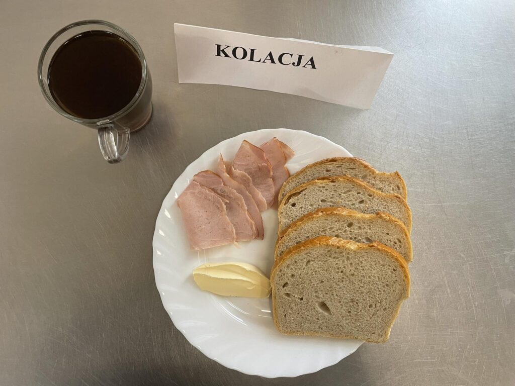 Zdjęcie kolacji złożonej z: konserwy wojskowej, pomidora, chleba, margaryny oraz herbaty.