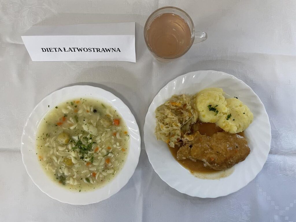 Zdjęcie obiadu złożonego z: zupy kalafiorowej z makaronem, bitki, ziemniaków, kapusty kiszonej oraz kompotu.
