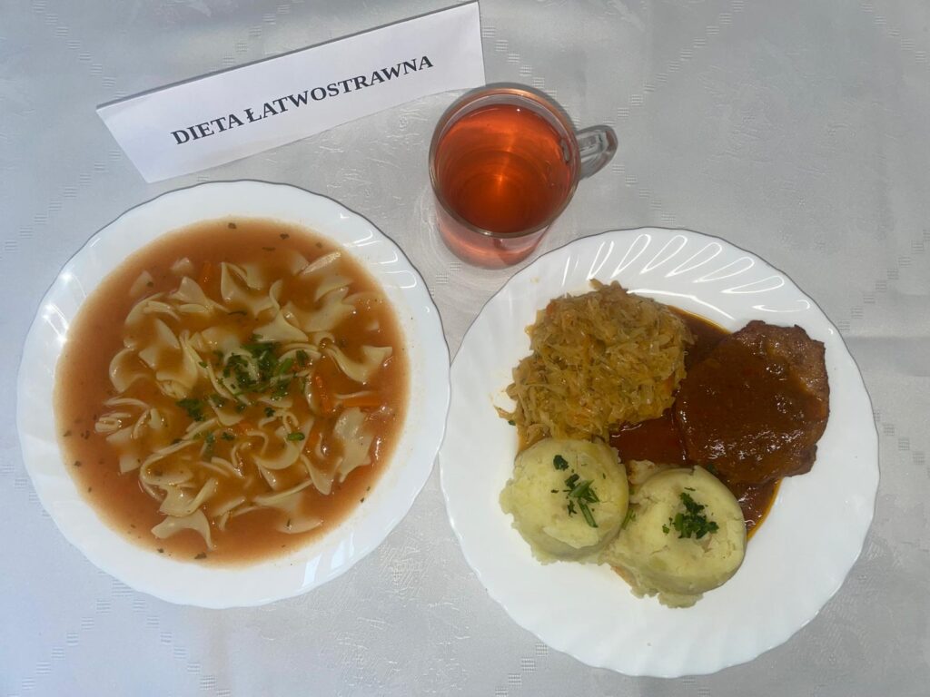 zdjęcie obiadu złożonego z: zupy pomidorowej z makaronem, kotleta schabowego, ziemniaków, kapusty smażonej oraz kompotu.