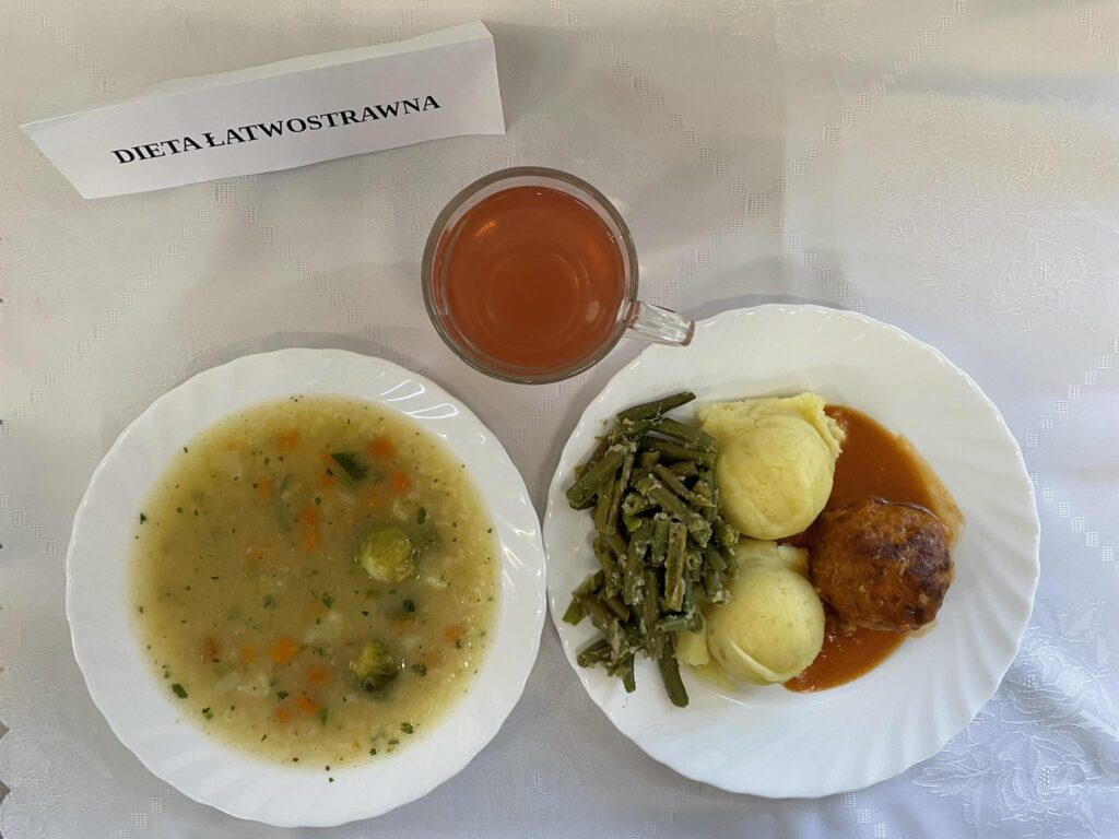 Zdjęcie obiadu złożonego z: zupy koperkowej z ryżem, pulpet w sosie pomidorowym, ziemniaków, fasolo szparagowej oraz kompotu.