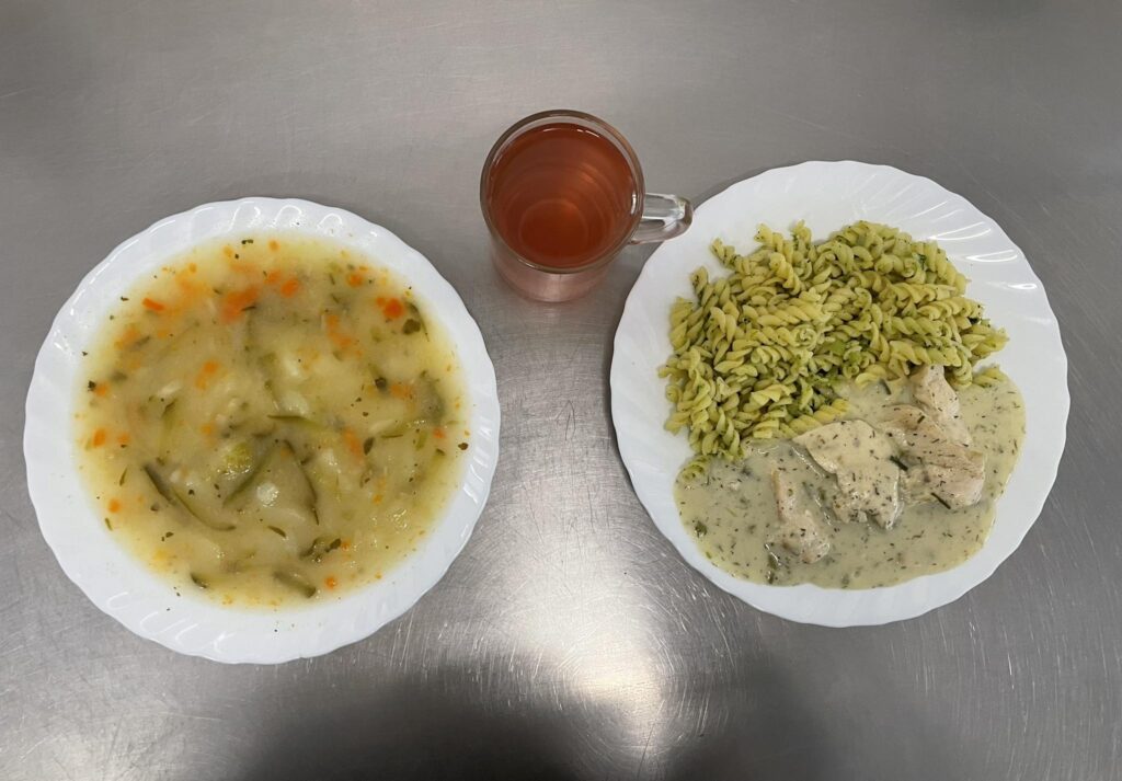 Zdjęcie obiadu złożonego z: zupy ogórkowej z ryżem, makaron penne z kurczakiem i brokułem w sosie serowym oraz kompotem.