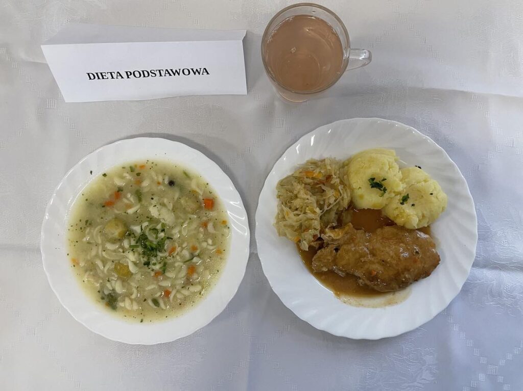Zdjęcie obiadu złożonego z: zupy kalafiorowej z makaronem, bitki, ziemniaków, kapusty kiszonej oraz kompotu.
