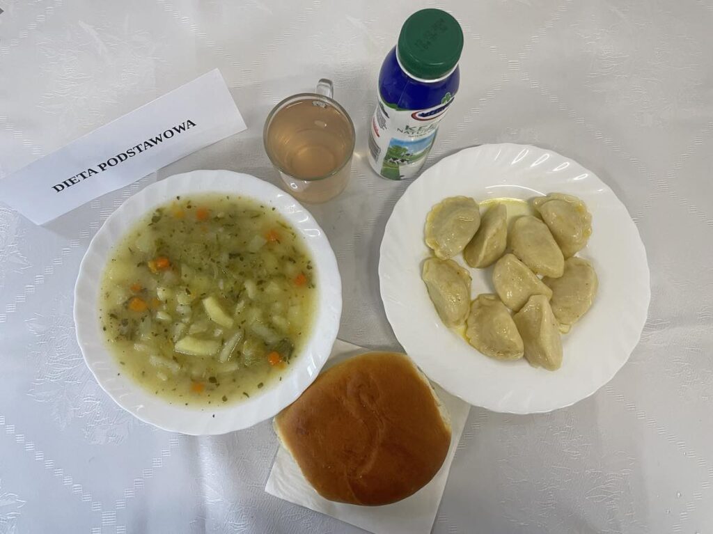 Zdjęcie obiadu złożonego z: zupy kalafiorowej z makaronem, pierogów, kefiru, kompotu oraz drożdżówki na podwieczorek
