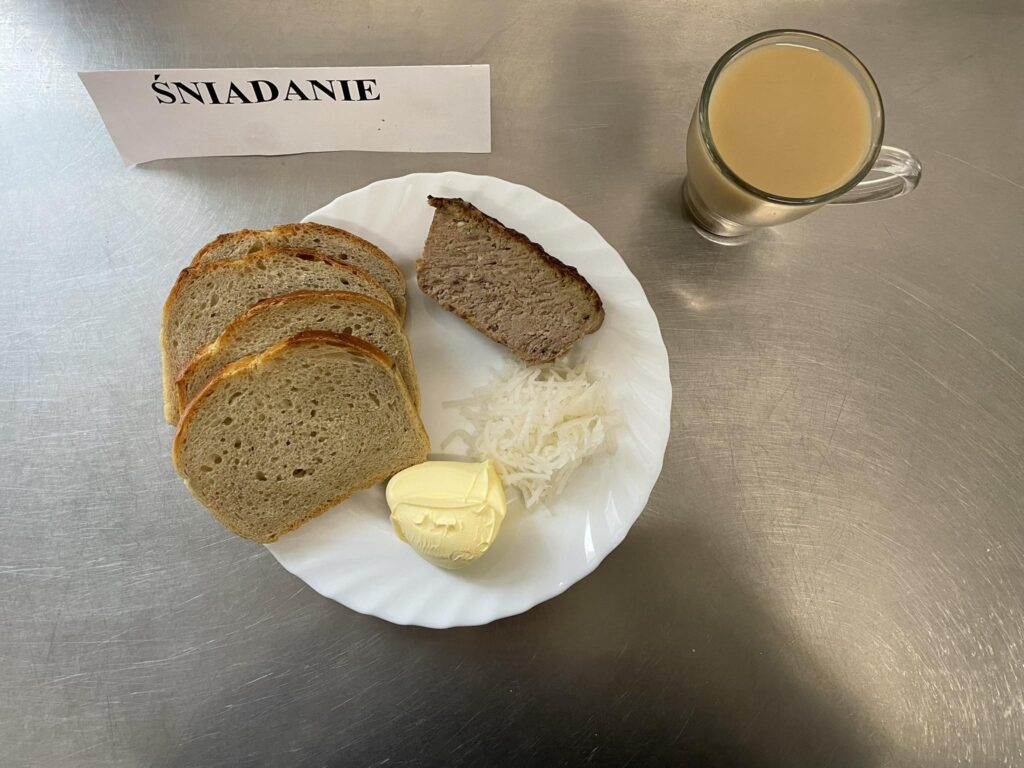 zdjęcie śniadania złożonego z: pasztetu pieczonego, rzodkiewki białej ,chleba pszennego, margaryny oraz kawy z mlekiem.