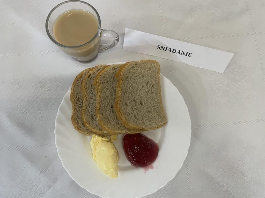 Śniadanie złożone z: chleba, margaryny, dżemu śliwkowego nie słodzonego, kawa zbożowa z mlekiem oraz jabłko