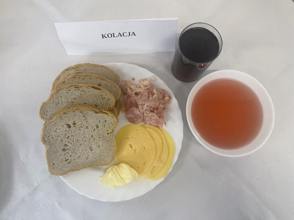 Zdjęcie kolacji złożonej z: chleba mazowieckiego, margaryny, sera edamskiego, sałaty zielonej oraz herbaty.