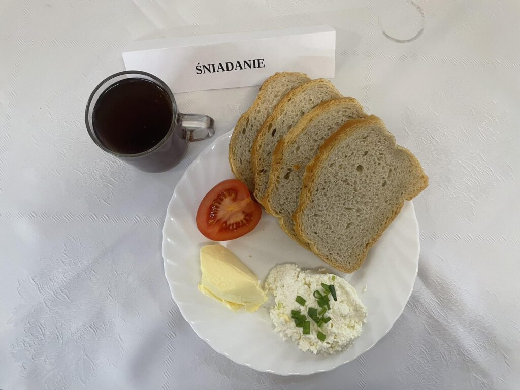 Zdjęcie śniadania złożonego z: chleba mazowieckiego, margaryny śniadaniowej, twarożku ze szczypiorkiem oraz herbatą