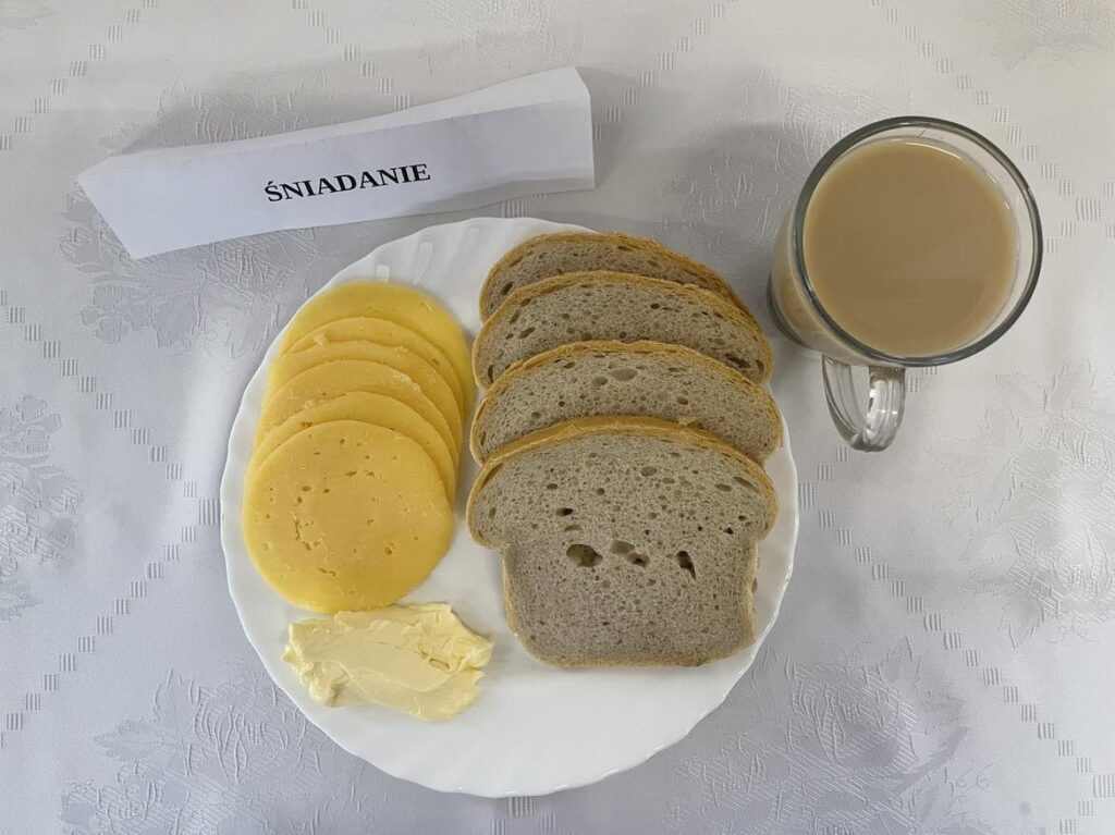 zdjęcie śniadania złożonego z: chleba mazowieckiego, margaryny śniadaniowej,, kawy zbożowej, mleka oraz sera edamskiego. 