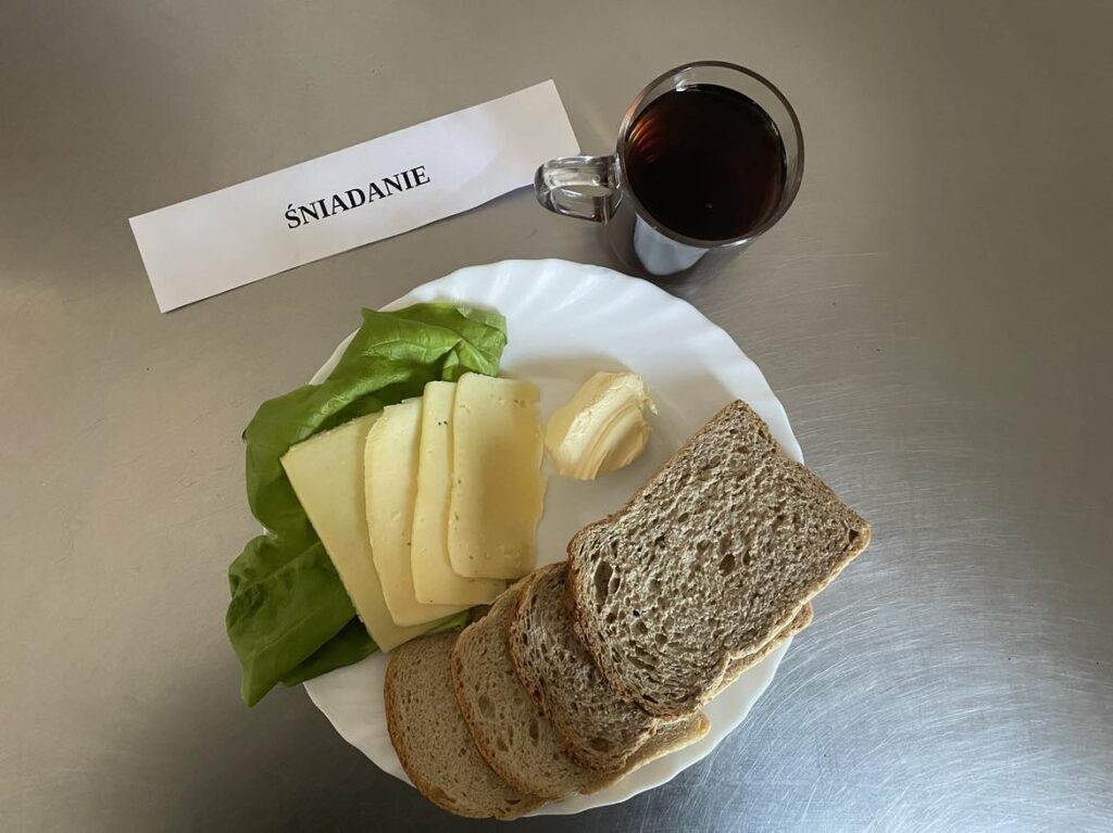 Śniadanie złożone z: chleba pszennego oraz razowego, margaryny, sera edamskiego, sałaty oraz herbaty.
