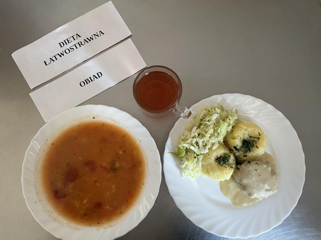 obiad złożony z: zupy pomidorowej, ziemniaków purree, pulpetów w sosie selerowym, surówka z kapusty pekińskiej, ogórka kiszonego i pora oraz kompot z jabłek.