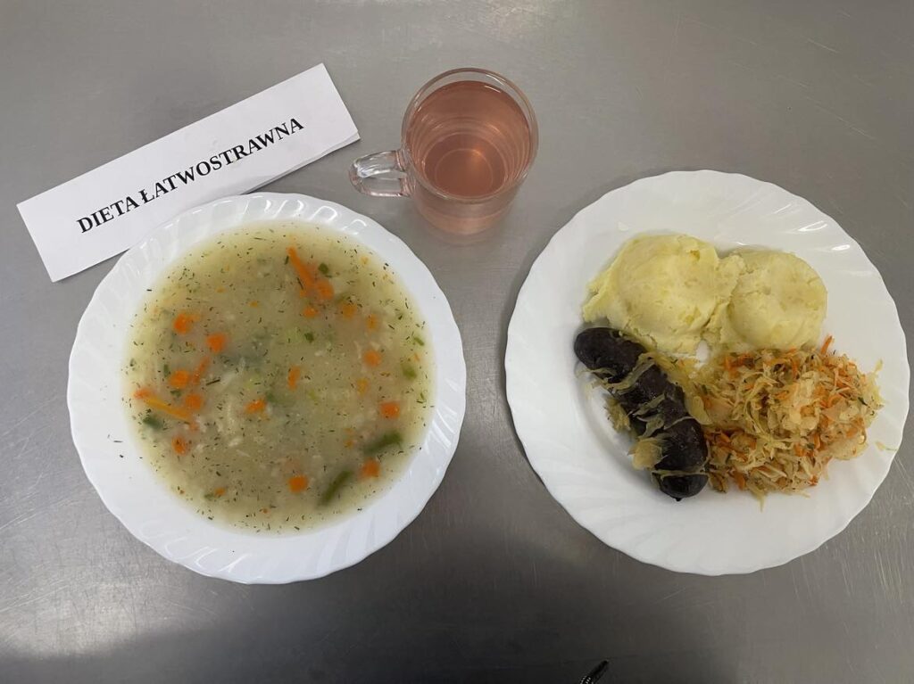 Obiad złożony z: zupy koperkowej, ziemniaków puree, kiszki krwistej, surówki z kapusty kiszonej oraz kompot z jabłek (z cukrem).