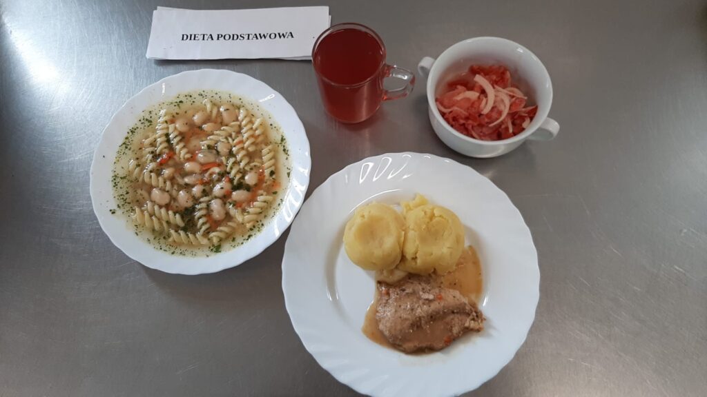 Obiad złożony z: zupy fasolowej, ziemniaków puree, bitki w sosie, sałatki z pomidorów oraz kompotu z jabłek (z cukrem).