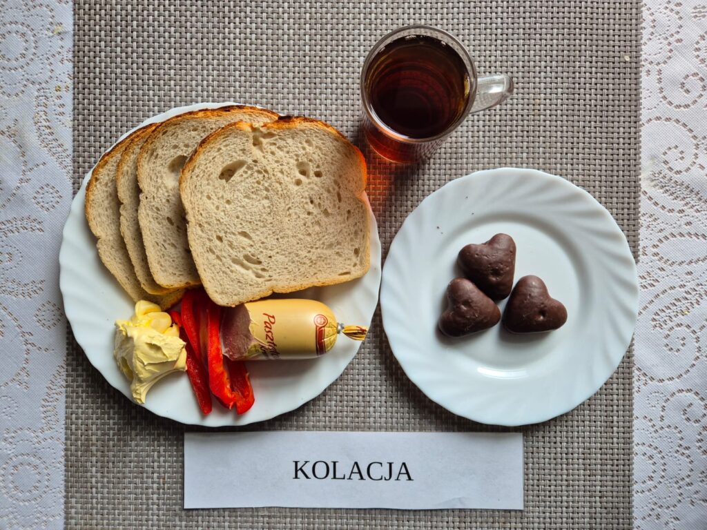 Na zdjęciu znajduję się posiłek w którego skład wchodzi Chleb pszenny, Margaryna Śniadaniowa, Pasztet drobiowy kremowy, Pierniczki oraz Herbata czarna
