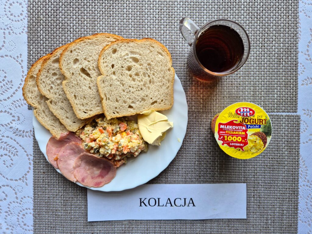 Na zdjęciu znajduję się posiłek w którego skład wchodzi Chleb pszenny, Margaryna Śniadaniowa, Sałatka jarzynowa oraz Herbata czarna