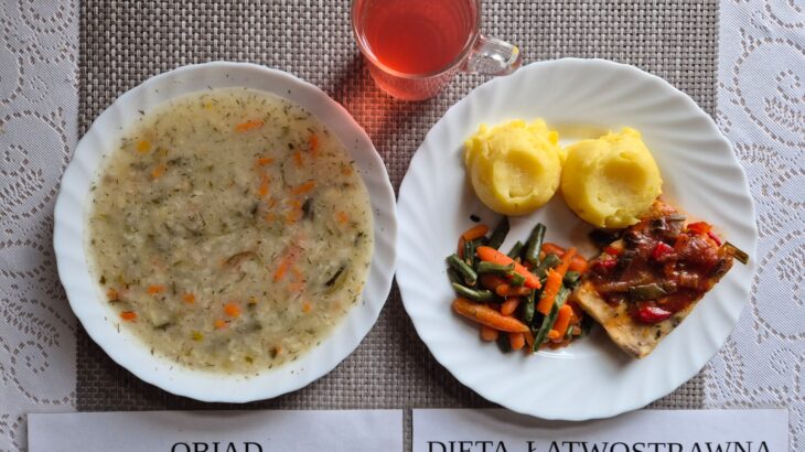 Na zdjęciu znajduję się posiłek w którego skład wchodzi Zupa ogórkowa z ryżem, Ryba pieczona w warzywach, ziemniaki, Marchewka mini oraz kompot