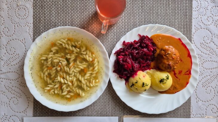 Na zdjęciu znajduję się posiłek w którego skład wchodzi Zupa jarzynowa z makaronem, Pulpet drobiowy w sosie pomidorowym, Ziemniaki, Surówka z buraka, Kompot z jabłek