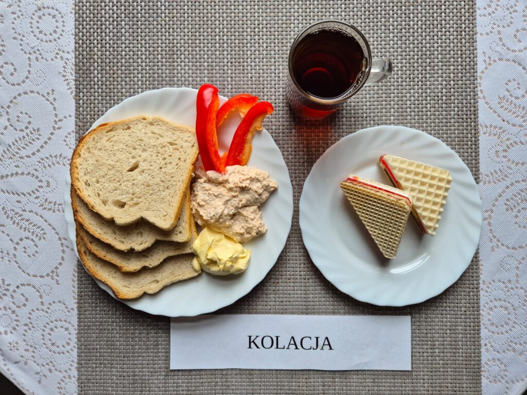 Na zdjęciu znajduję się posiłek w którego skład wchodzi Chleb pszenny, Margaryna Śniadaniowa, twarożek z makrelą, papryka, andruty oraz Herbata czarna