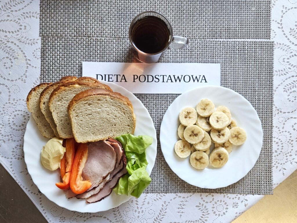 Zdjęcie przedstawia kolacje. Chleb z wędliną, masłem, papryką i sałatą oraz na drugim talerzu pokrojonego banana