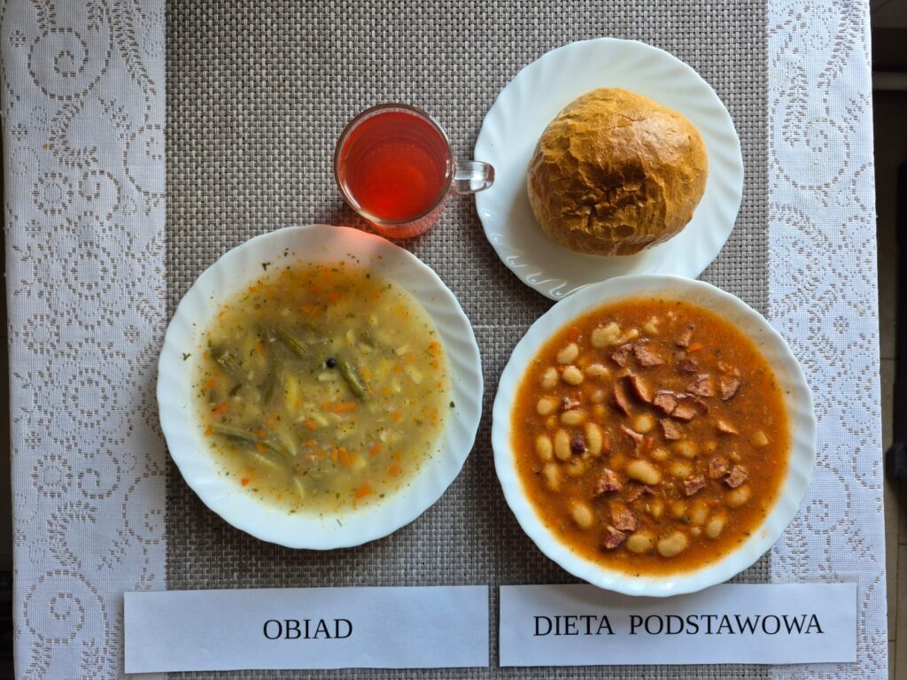 Na zdjęciu znajduję się posiłek w którego skład wchodzi Zupa jarzynowa z fasolką szparagową, Fasolka po bretońsku, Bułka pszenna oraz Kompot