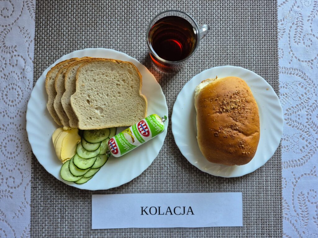 Na zdjęciu znajduję się posiłek w którego skład wchodzi Chleb pszenny, Margaryna Śniadaniowa, Ser topiony, Ogórek zielony oraz Herbata czarna