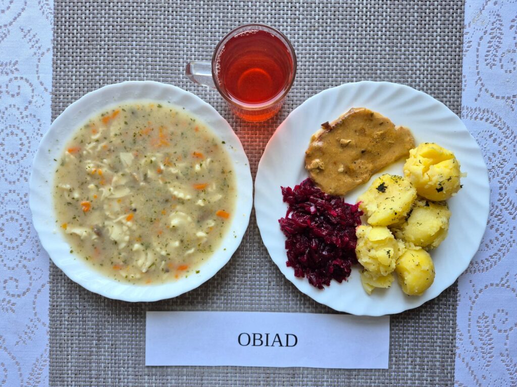 Na zdjęciu znajduję się posiłek w którego skład wchodzi Zupa pieczarkowa z makaronem, Ziemniaki, Bitka wieprzowa, Kalafior z bułka tartą oraz Kompot z jabłek