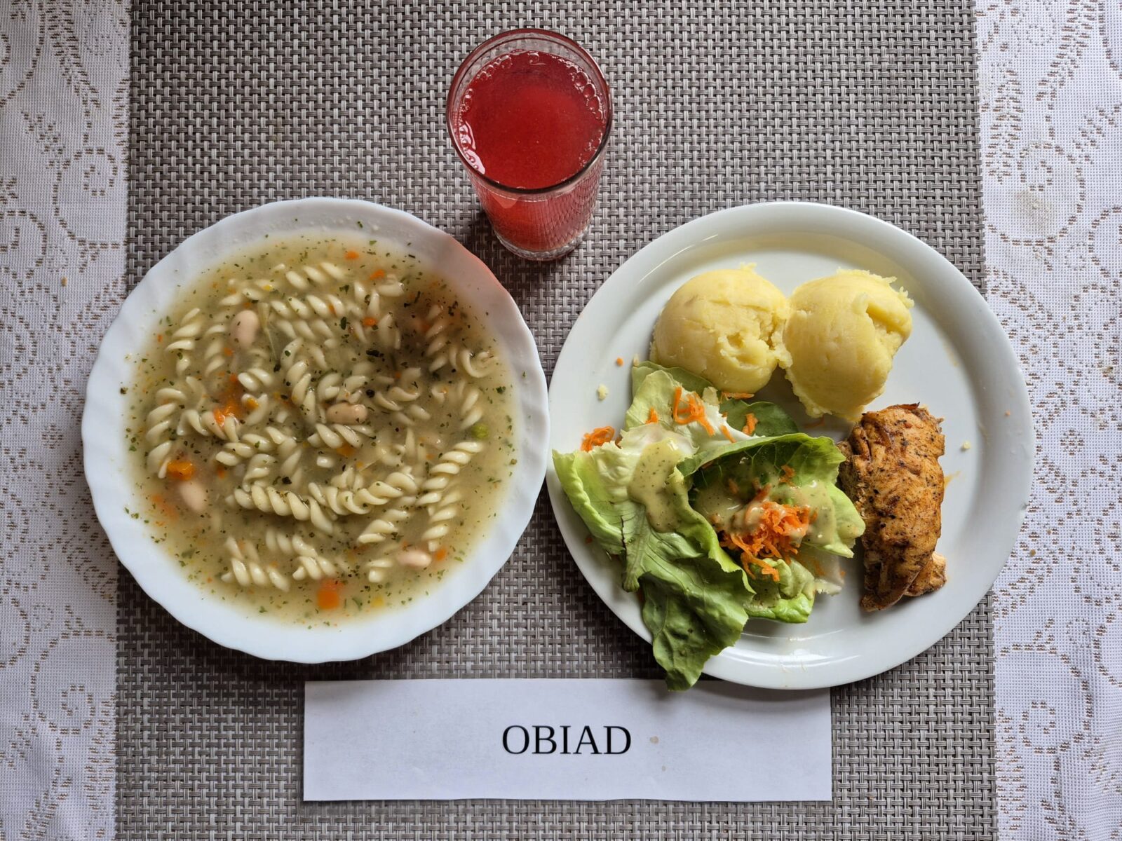 Na zdjęciu znajduję się posiłek w którego skład wchodzi Zupa fasolowa z makaronem, Filet z kurczaka pieczony, Ziemniaki, Sałata masłowa z marchewką oraz Kompot z jabłek