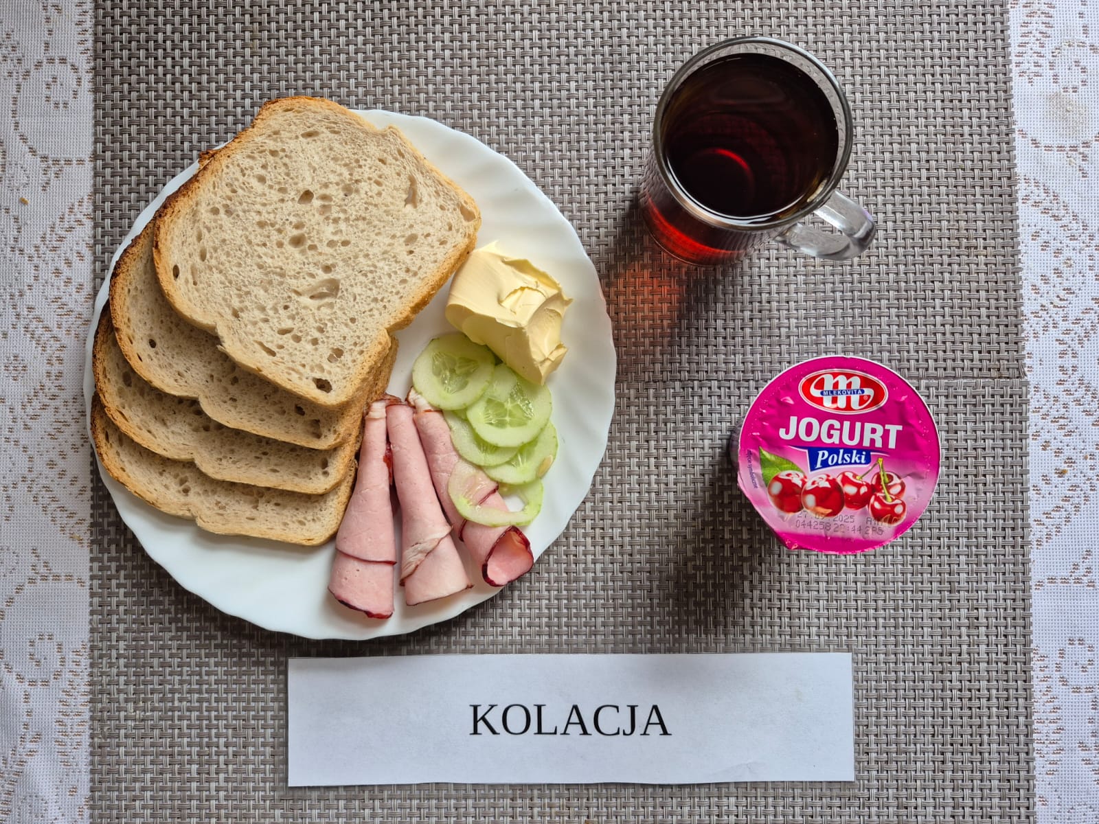 Na zdjęciu znajduję się posiłek w którego skład wchodzi Chleb pszenny, Margaryna Śniadaniowa, wędlina wieprzowa oraz herbata czarna