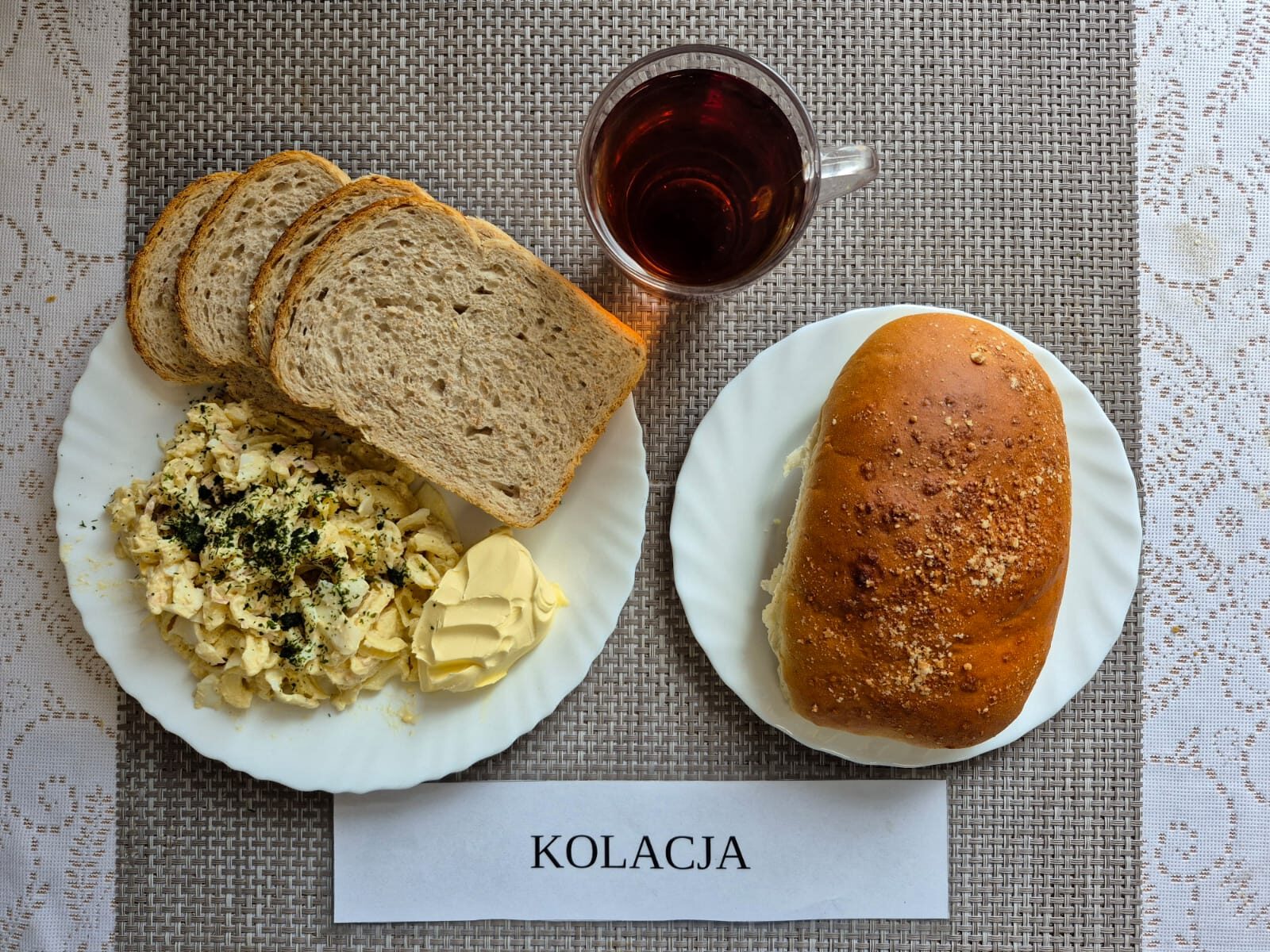 Na zdjęciu znajduję się posiłek w którego skład wchodzi Chleb pszenny, Margaryna Śniadaniowa, Pasta z tuńczyka, jajka i makaronu, sałata masłowa oraz Herbata czarna