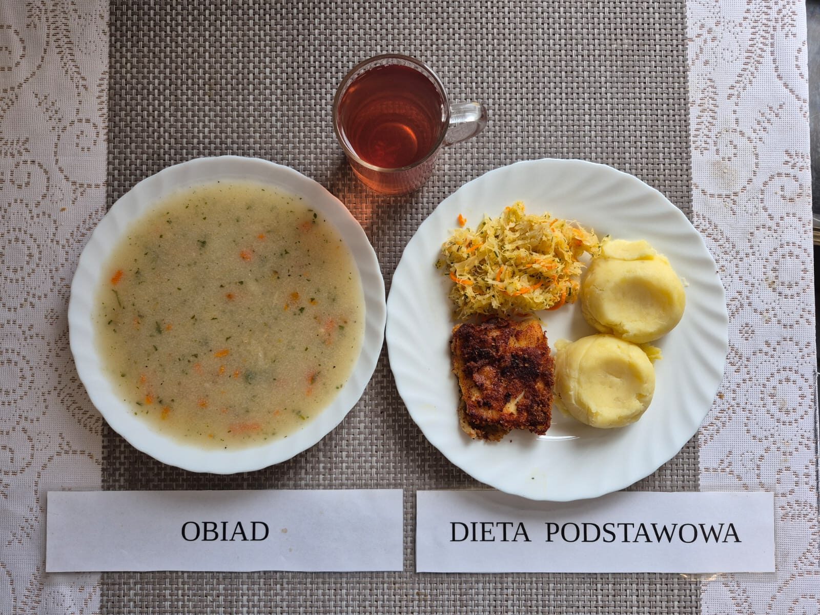 Na zdjęciu znajduję się posiłek w którego skład wchodzi Zupa jarzynowa ziemniakami i groszkiem cukrowym, ziemniaki, Ryba smażona, surówka z kapusty kiszonej oraz kompot