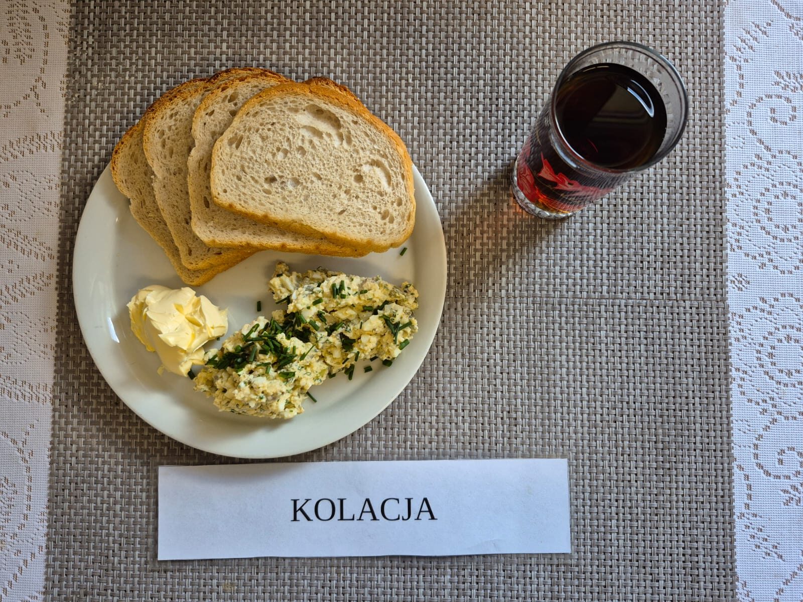 Na zdjęciu znajduję się posiłek w którego skład wchodzi Chleb pszenny, Margaryna Śniadaniowa, Pasta z jajek, ogórek kiszony oraz Herbata czarna