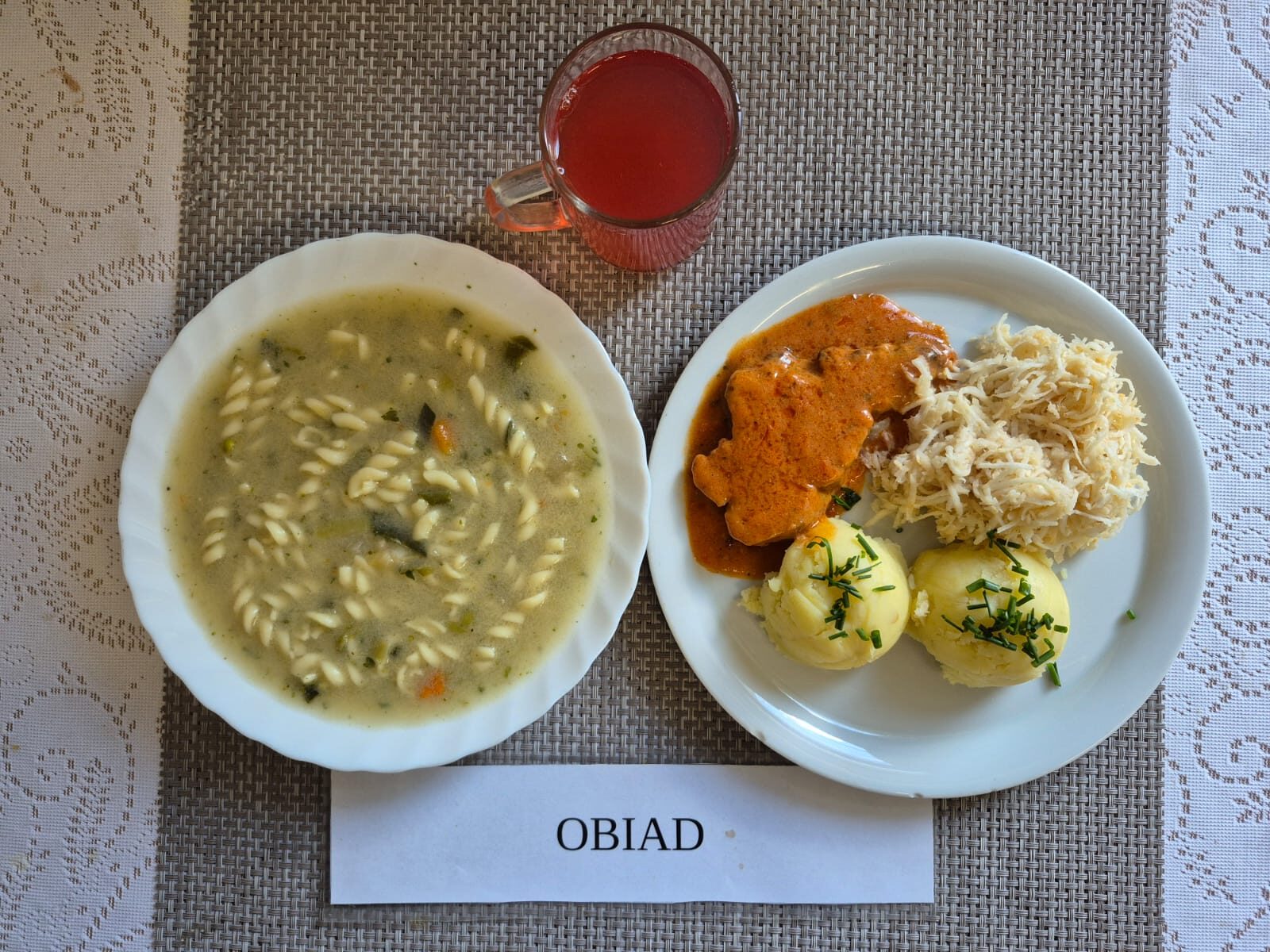 Na zdjęciu znajduję się posiłek w którego skład wchodzi Zupa porowa z makaronem, Ziemniaki, Karkówka w sosie ketchupowym, Surówka z selera oraz Kompot z jabłek