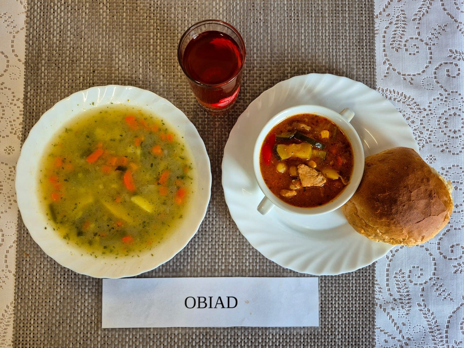 Na zdjęciu znajduję się posiłek w którego skład wchodzi Zupa makaronowa, Leczo z mięsem wieprzowym i cukinią i ziemniakami, Bułka pszenna oraz kompot