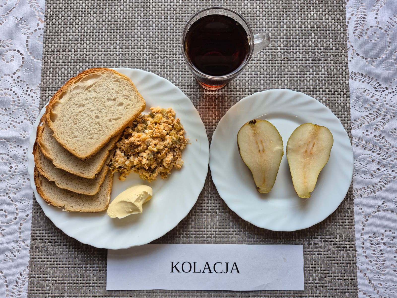 Na zdjęciu znajduję się posiłek w którego skład wchodzi Chleb pszenny, Margaryna śniadaniowa, Sałatka z makreli, jajka i ogórka kiszonego oraz Herbata czarna