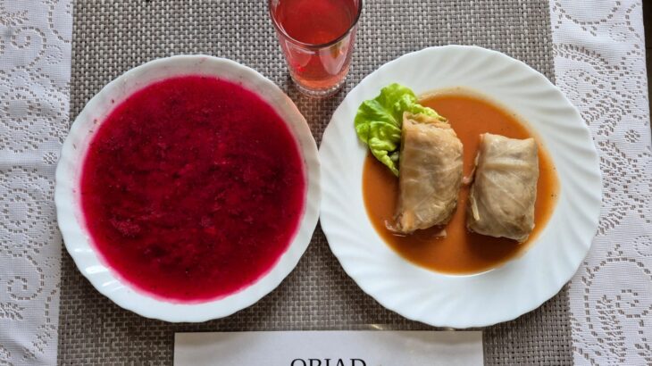 Na zdjęciu znajduję się posiłek w którego skład wchodzi Zupa barszcz ukraiński z ziemniakami, Gołąbki z sosem pomidorowym oraz kompot z jabłek