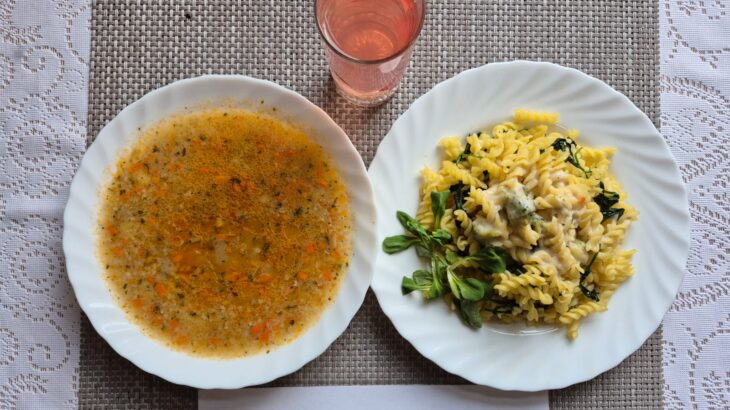 Na zdjęciu znajduję się posiłek w którego skład wchodzi Zupa krupnik z ziemniakami, Makaron z sosem śmietanowym brokułem i świeżym szpinakiem oraz kompot z jabłek